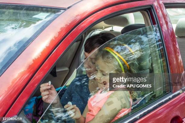 Amber Grafton and her daughter Jemma Grafton pray inside her car during an online Sunday Service lead by Pastor Tim Thompson at the Christian '412...