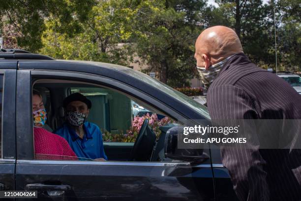 Pastor Tim Thompson prays in a parking lot with people who attended to an online Sunday Service inside their cars at the Christian '412 Church...
