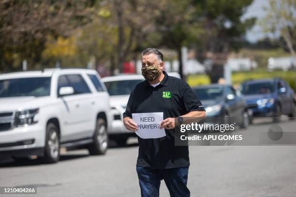 Simon Cooper offers prayers to people who attended an on line Sunday Service inside their cars at the Christian '412 Church Murrieta' parking lot on...