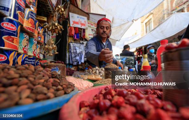 Yemeni vendor waits for costumers in the old city market of the capital Sanaa ahead of the holy Muslim fasting month of Ramadan, on April 18, 2020. -...