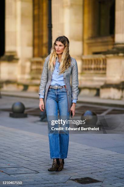 Veronika Heilbrunner wears a blue shirt, a gray jacket with buttons, a belt with metallic buckle, blue denim jeans pants, outside Vuitton, during...