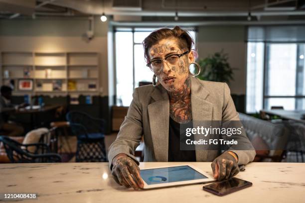 portrait of tattooed businesswoman working with digital tablet at lobby office - statement imagens e fotografias de stock