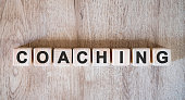 Coaching text word on wooden cubes on wooden background