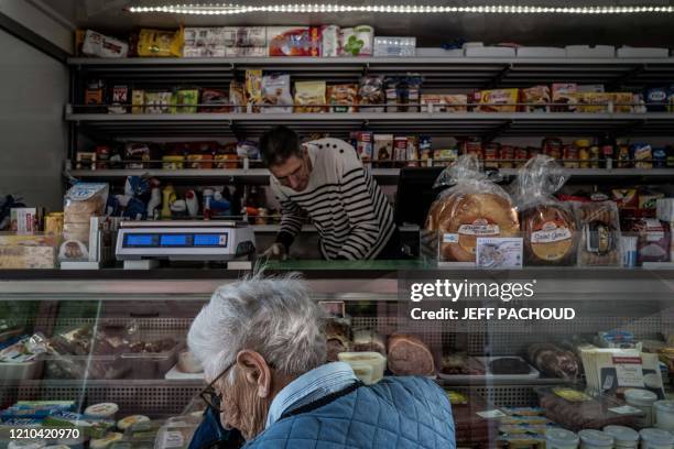 French ambulant grocer Claude Mottet stands in his truck as an elderly woman buys him supplies during his daily tour to deliver food to his clients...