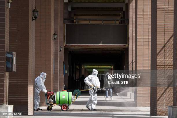 Staff members spray disinfectant in the compounds of a school as it prepares to reopen after the term opening was delayed due to the COVID-19...