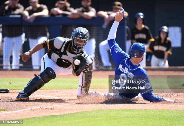 Ryan McBroom of the Kansas City Royals safely slides into home plate on a double by Kyle Isbel as Francisco Mejia of the San Diego Padres waits for...