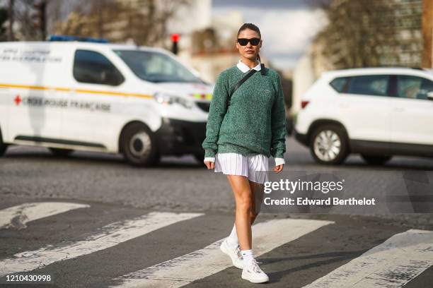 Sophia Roe wears sunglasses, a white polo shirt, a green pullover from Lacoste, a white pleated mini skirt, white socks, sneakers, outside Lacoste,...