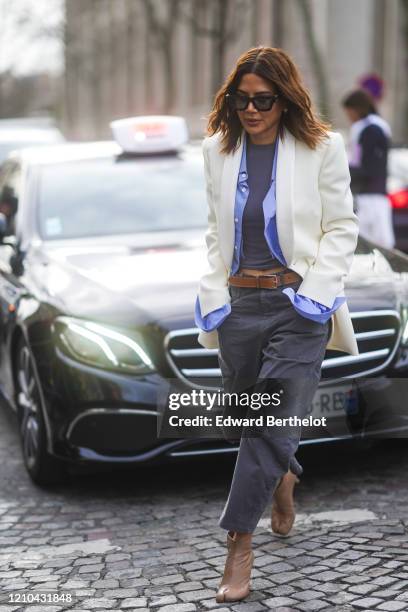 Christine Centenera wears sunglasses, a white jacket, a mauve shirt, a t-shirt, a brown leather belt, gray pants, brown leather shoes, outside Miu...