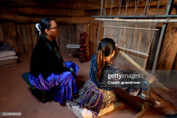 een navajo grootmoeder leert haar jonge kleindochter hoe te weven op een weefgetouw - navajo hogan stockfoto's en -beelden