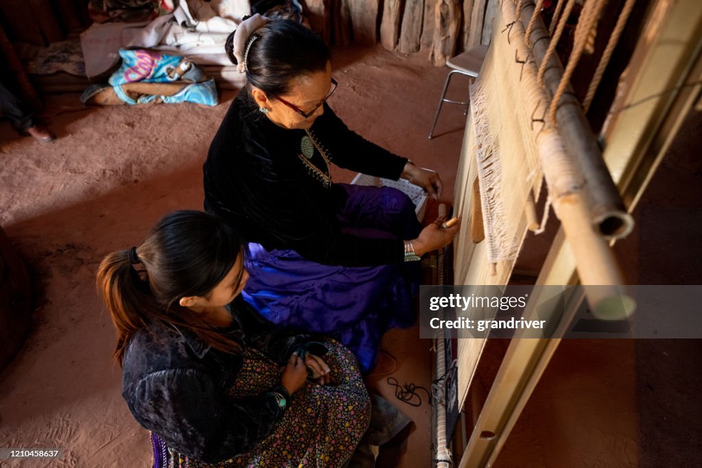 A Navajo Grandmother Teaching Her Young Granddaughter How To Weave On A Loom