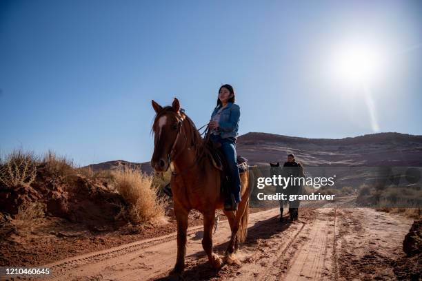 a native american sister and her brother riding horses on a dirt road with their dog - horseback riding arizona stock pictures, royalty-free photos & images