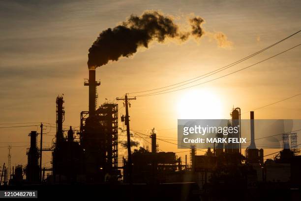 The sun sets behind smoke rising from the LyondellBasell-Houston Refining plant in Houston, Texas, on April 20, 2020. US oil prices crashed to...