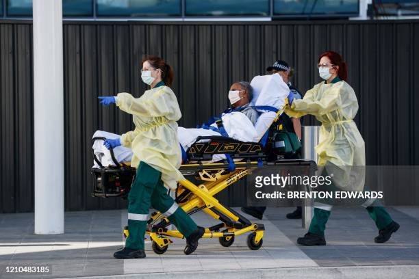 An Australian resident with a pre-existing condition is stretchered into an awaiting ambulance upon landing after a repatriation flight carrying over...