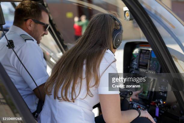 helicopter pilot with female colleague checking dashboard settings before flight - helicopter pilot stock pictures, royalty-free photos & images