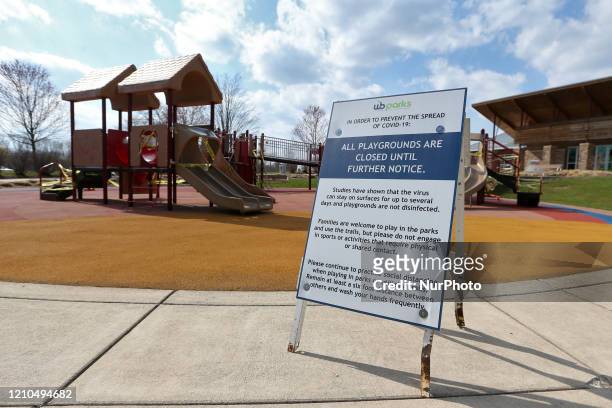 Signage is displayed explaining closure of playground structures, which are covered in caution tape to restrict use, as part of Governor Gretchen...