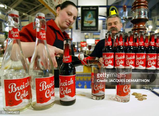 Une serveuse d'un stand breton du salon de l'agriculture, qui se tient jusqu'au 02 mars 2003 à Paris, prépare un verre de "Breizh cola" le 25 février...