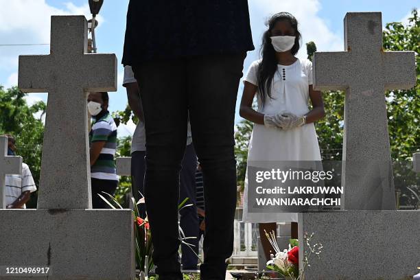 Relatives pay their respects at a graveyard for St. Sebastian's Church bomb blasts victims in Negombo on April 21 to mark the first anniversary of...