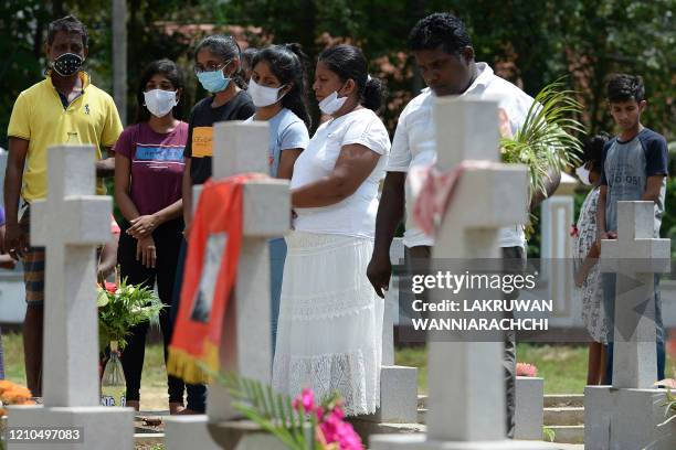 Relatives pay their respects at a graveyard for St. Sebastian's Church bomb blasts victims in Negombo on April 21 to mark the first anniversary of...