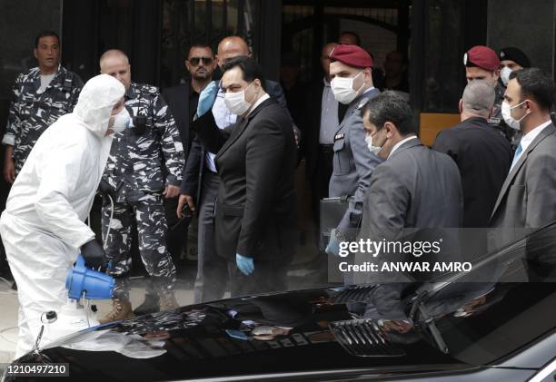 Lebanese Prime Minister Hassan Diab wearing a protective mask gets disinfected before entering the Unesco Palace for a parliament meeting, in the...