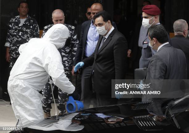 Lebanese Prime Minister Hassan Diab wearing a protective mask gets disinfected before entering the Unesco Palace for a parliament meeting, in the...