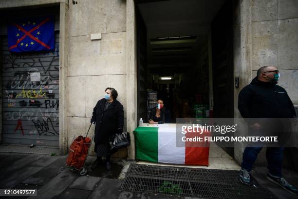 Woman wearing a face mask waits with her trolley for free shopping distributed by activists of Italian neo-fascist movement Casapound on April 21,...