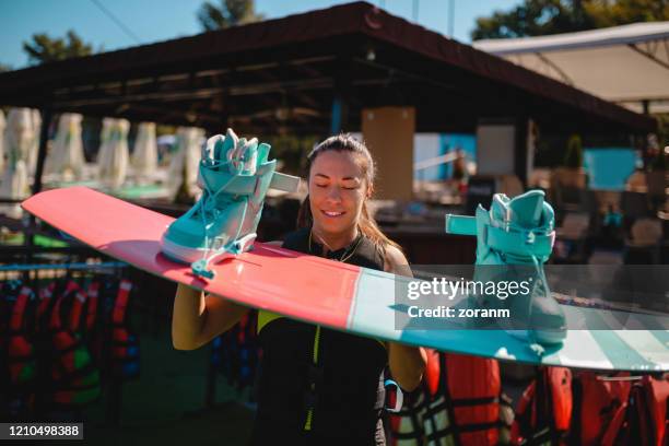young woman holding wakeboard with boots - wakeboarding stock pictures, royalty-free photos & images