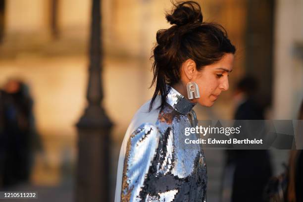 Guest wears a silver shiny glitter turtleneck dress, an A-shaped earring, outside Vuitton, during Paris Fashion Week - Womenswear Fall/Winter...