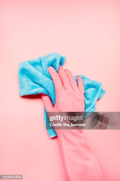 hand in pink glove with blue cleaning rag on pink background, house cleaning - glove stockfoto's en -beelden