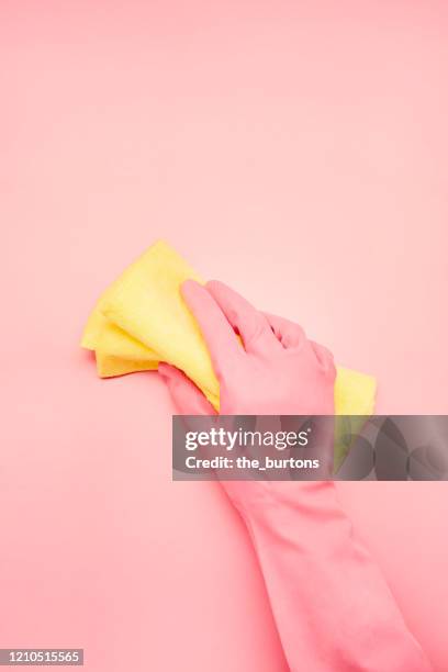 hand in pink glove with cleaning cloth on pink background, spring cleaning - roze handschoen stockfoto's en -beelden