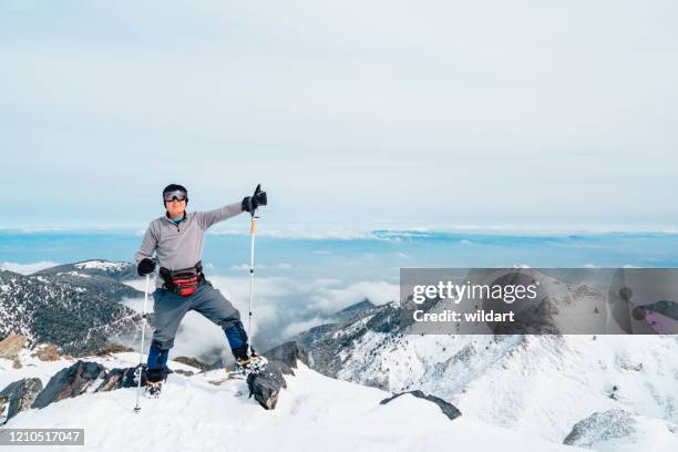 älterer bergsteiger feiert erfolg, indem er im winter die arme auf dem gipfel eines höhenberges öffnet - ice pick stock-fotos und bilder