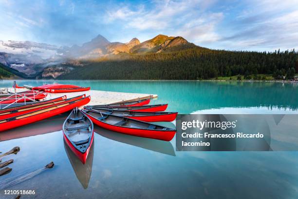 lake louise, canoe and kayak on calm water at sunrise. banff, canadian rockies, canada - lake louise stock pictures, royalty-free photos & images