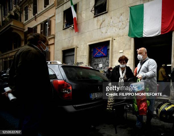 Members of a family carry shopping bags handed for free by activists of Italian neo-fascist movement Casapound on April 21, 2020 in Rome, during the...