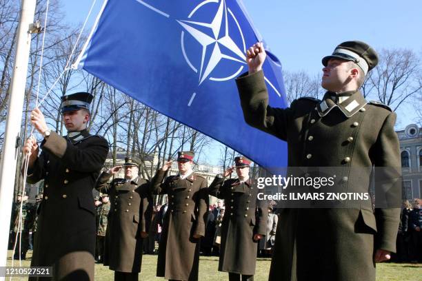 Latvian officers stand guard during the NATO flag rising ceremony in front of the Presidents castle in Riga 02 April 2004. Bulgaria, Estonia, Latvia,...