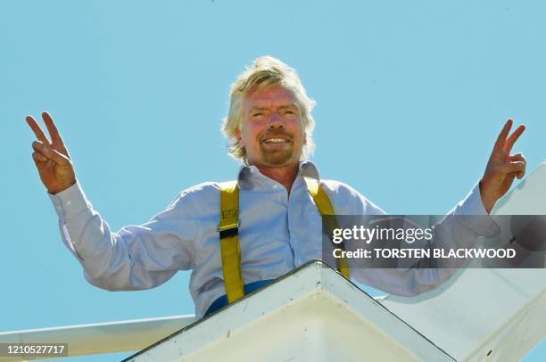 Virgin Group Chairman Richard Branson flashes victory signs from a cherry-picker near Virgin Blue's new domestic terminal at Sydney Airport, 06...