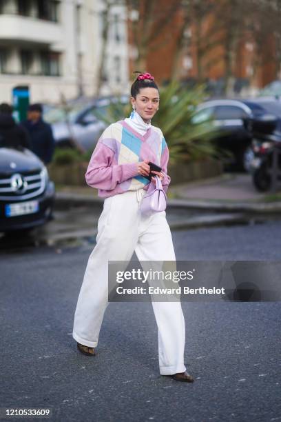 Guest wears a white turtleneck pullover, a pink argyle pattern printed wool pullover, white pants, a purple leather bag, pointy shoes, earrings,...