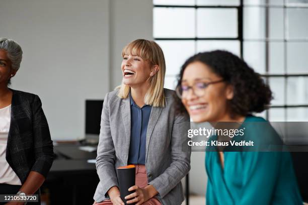 excited businesswoman looking away in office - formal stock-fotos und bilder