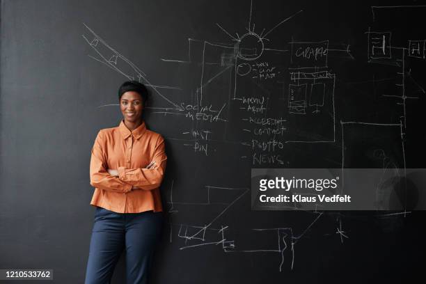 smiling entrepreneur standing in office board room - blackboard women stock pictures, royalty-free photos & images