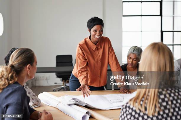 entrepreneur discussing plan at bright workplace - business people group brown stock pictures, royalty-free photos & images