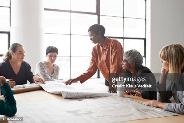 entrepreneurs discussing at table in bright office - business people group brown stock pictures, royalty-free photos & images