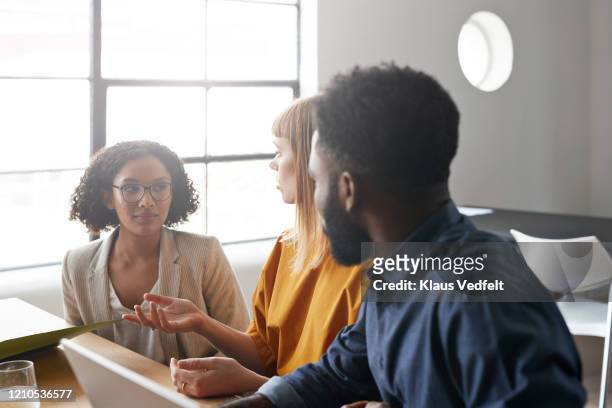 businesswoman discussing with colleagues in office - blue blazer stock pictures, royalty-free photos & images