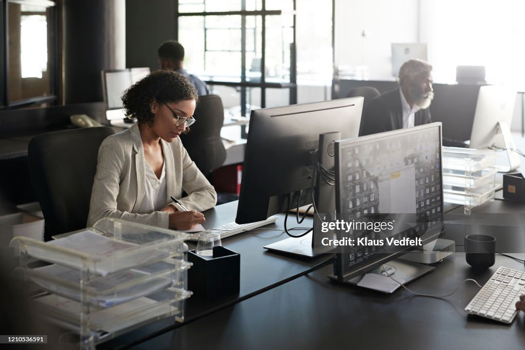 Businesswoman writing at modern desk in office