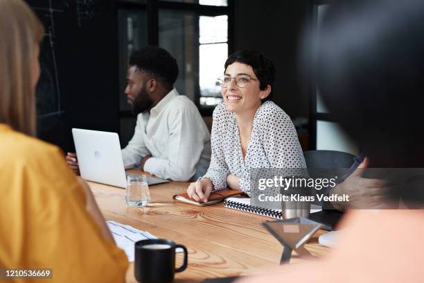 smiling businesswoman in meeting at workplace - compromiso de los empleados fotografías e imágenes de stock
