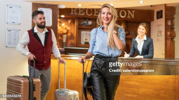 bellhop moving luggage on cart for hotel guest - star hotel stock pictures, royalty-free photos & images