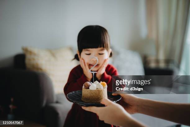 portrait of a cute little girl feeling surprised and excited when her mother presenting a birthday cake and celebrating her two years old birthday at home - 2 3 years stock pictures, royalty-free photos & images
