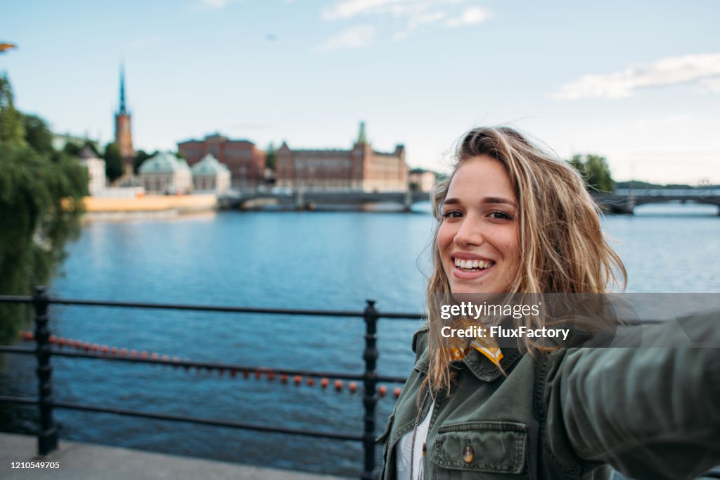 Modern fashionable woman taking photo of hersefl in front of Gamla Stan