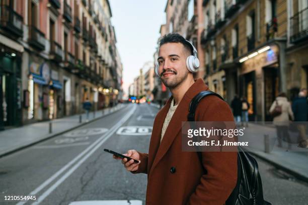 man with headphones and mobile phone walking on the street - music city walk stock pictures, royalty-free photos & images