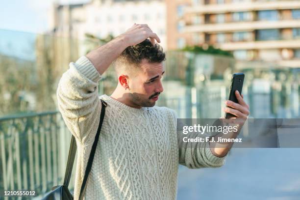 man getting good hair looking at his cellphone - combing foto e immagini stock