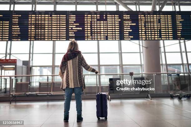 mujer leyendo la tabla de salida en el aeropuerto - cancelación fotografías e imágenes de stock