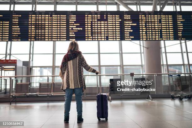 donna che legge il tabellone delle partenze in aeroporto - partire foto e immagini stock