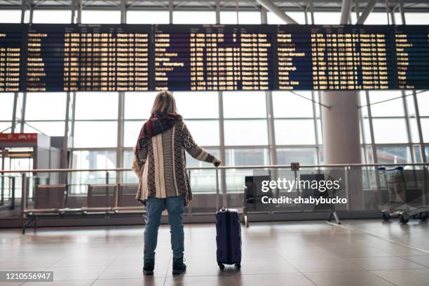 woman reading departure board on airport - cancelamento imagens e fotografias de stock